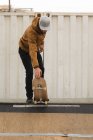 Stylish male skateboarder skating on skateboard ramp at skateboard court — Stock Photo