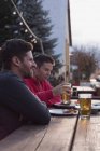 Jovens amigos desfrutando de suas bebidas no pub ao ar livre — Fotografia de Stock