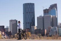 Чоловік використовує мобільний телефон під час прогулянки з велосипедом у місті в сонячний день — стокове фото