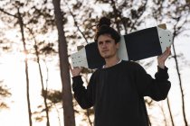 Junger männlicher Skateboarder trägt Skateboard auf Schultern — Stockfoto