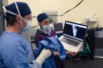 Enfermeira mostrando relatório de raio-x para cirurgião masculino no laptop no hospital — Fotografia de Stock