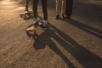 Low section of skateboarders skating on country road — Stock Photo