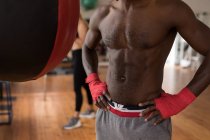 Средняя секция мужского боксера, стоящего с руками на бедрах в фитнес-студии — стоковое фото
