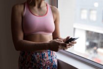 Mid section of female boxer using mobile phone in fitness studio — Stock Photo