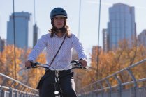 Молодий чоловік їде на велосипеді на мосту в місті — стокове фото