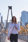 Молодий чоловік тримає чашку кави на мосту в місті — стокове фото