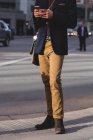 Section basse de l'homme utilisant un téléphone portable tout en marchant dans la rue — Photo de stock