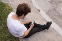 Vue grand angle de l'homme en utilisant le téléphone mobile au parc de skateboard — Photo de stock
