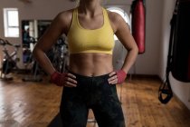 Mid section of female boxer standing with hands on hips in fitness studio — Stock Photo