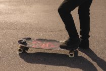 Крупный план катания на скейтборде по проселочной дороге — стоковое фото
