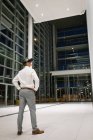 Rückansicht eines Geschäftsmannes, der nachts sein Headset außerhalb des Büros erlebt — Stockfoto