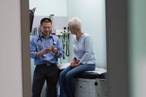 Jovem asiático médico masculino e paciente sênior discutindo sobre modelo de orelha na clínica — Fotografia de Stock
