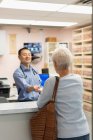 Vorderseite eines jungen asiatischen männlichen Arztes, der Medikamente für Patienten in der Klinik verschreibt — Stockfoto