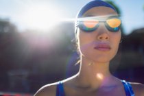Vista frontal de uma nadadora com óculos de natação olhando para a piscina em um dia ensolarado — Fotografia de Stock
