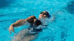 Vista de ángulo alto de la joven nadadora nadando espalda en la piscina - foto de stock