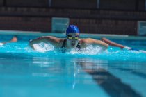 Front view of young female swimmer with swim goggle swimming at swimming pool — Stock Photo