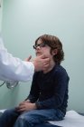 Vista lateral de jovem asiático médico masculino falando com menino na clínica — Fotografia de Stock