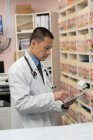 Vue latérale de jeune asiatique mâle médecin tenant tablette numérique dans la clinique — Photo de stock