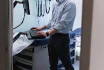 Metà sezione giovane asiatico maschio medico working su computer in clinica — Foto stock