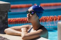 Side view of young female swimmer standing in swimming pool — Stock Photo