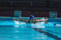Vista frontal de una joven nadadora con gafas de natación nadando en la piscina - foto de stock