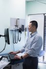 Visão lateral de jovem asiático médico masculino trabalhando no computador na clínica — Fotografia de Stock