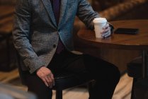 Parte do meio do empresário tomando café na mesa no escritório — Fotografia de Stock