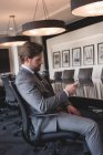 Вид сбоку сидящего бизнесмена с помощью мобильного телефона в конференц-зале в офисе — стоковое фото