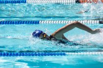 Vista laterale di una giovane nuotatrice che striscia in piscina in una giornata di sole — Foto stock