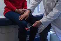 Mid seção de jovem ásia masculino médico examinando um sênior paciente com reflexo martelo no o clínica — Fotografia de Stock