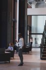 Вид сбоку на стоящего бизнесмена, разговаривающего по мобильному телефону в вестибюле современного офиса — стоковое фото
