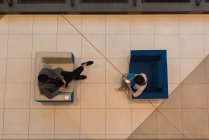 Vista superior de pessoas de negócios usando telefone celular sentado nas poltronas modernas no lobby no escritório — Fotografia de Stock