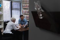 Giovane asiatico medico maschio e paziente anziano discutendo su tablet digitale in clinica — Foto stock