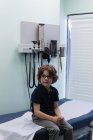 Vista frontal caucasiano menino paciente sentado na cama na clínica — Fotografia de Stock