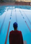 Vista traseira do jovem nadador envolto em toalha de pé perto da piscina — Fotografia de Stock