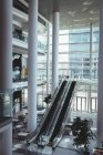 Vue surélevée de l'escalier roulant et espace vide spacieux à l'intérieur d'un bureau moderne avec un fond de bâtiment de la ville — Photo de stock