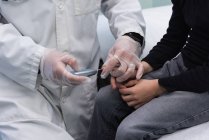 Mid seção de jovem ásia masculino médico examinando caucasiano menino paciente com glucometer no clínica — Fotografia de Stock