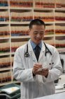 Vista frontal joven médico asiático prescribe medicamentos para el paciente en la clínica - foto de stock