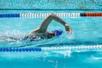 Vista lateral de uma jovem nadadora nadadora nadando rastejar na piscina em um dia ensolarado — Fotografia de Stock