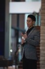 Вид збоку бізнесмена, який розмовляє на мобільному телефоні, маючи каву в сучасному офісі — стокове фото