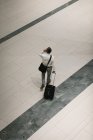 Підвищений вигляд бізнесмена з проїзною валіза розмовляє по мобільному телефону під час ходьби в коридорі — стокове фото