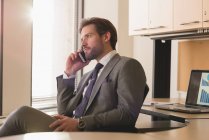 Вид сбоку бизнесмена, разговаривающего по мобильному телефону в современном офисе — стоковое фото