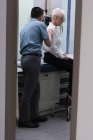 Seitenansicht eines jungen asiatischen männlichen Arztes bei der Untersuchung eines älteren Patienten in der Klinik — Stockfoto