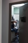 Vue latérale d'un jeune médecin asiatique qui examine une oreille de garçon caucasien avec un outil dans une clinique. Médecin masculin interagissant avec le patient — Photo de stock
