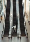 Elevated view of businessman on escalator in office — Stock Photo