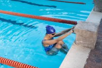 Vista de ángulo alto del nadador femenino colgando en el mango del bloque de partida en la piscina - foto de stock