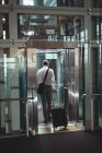 Вид ззаду бізнесмена з дорожньою сумкою, що входить в ліфт в офісі — стокове фото