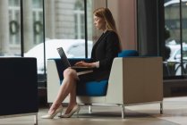 Side view of businesswoman using laptop in the lobby at office — Stock Photo