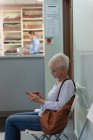 Side view of caucasian senior patient looking at mobile phone at clinic — Stock Photo