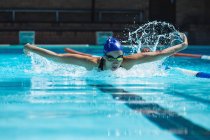 Vista frontal de uma jovem nadadora com óculos de natação nadando na piscina — Fotografia de Stock